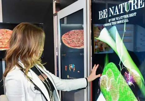 Mujer rubia interactuando con pantallas LED.