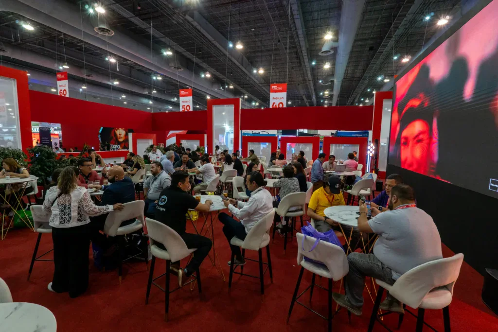 Escena del piso de exhibición en ExpoPublicitas, con visitantes interactuando en la zona de stands y áreas de networking al cierre del recorrido.