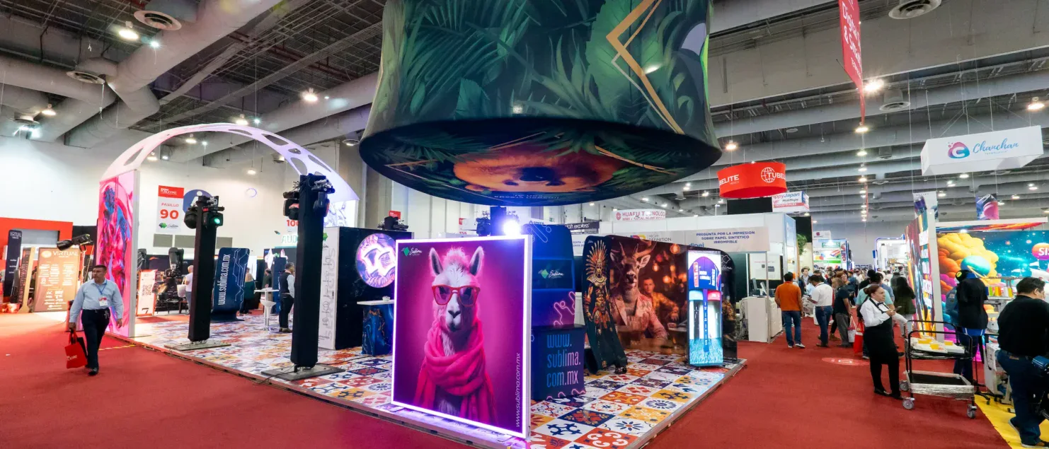 Stand BTL con diseño abierto y alto impacto visual que utiliza iluminación, gráfica y formatos envolventes para atraer al público y facilitar la circulación en un entorno de exposición profesional.