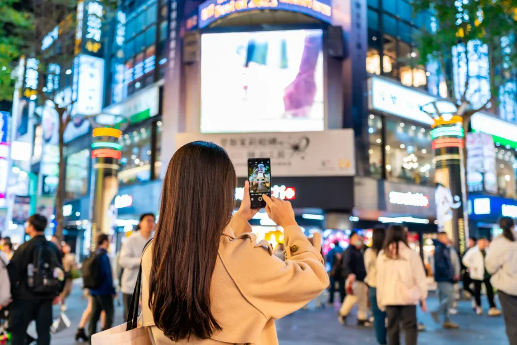 Persona interactuando con pantallas publicitarias digitales en un entorno urbano de alto tránsito, reflejo del impacto del DOOH en espacios públicos.