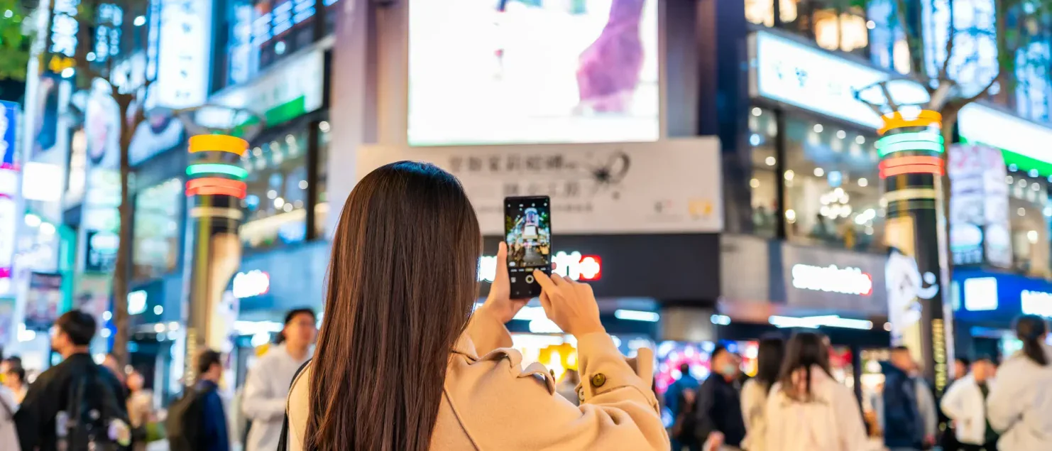 Persona interactuando con pantallas publicitarias digitales en un entorno urbano de alto tránsito, reflejo del impacto del DOOH en espacios públicos.