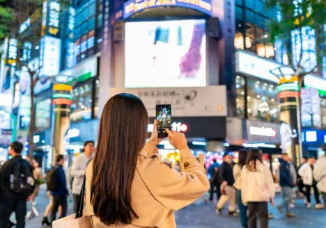 Persona interactuando con pantallas publicitarias digitales en un entorno urbano de alto tránsito, reflejo del impacto del DOOH en espacios públicos.